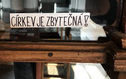 církev je zbytečná - samolepka nalepená někým na dveřích církevní instituce / -ima-